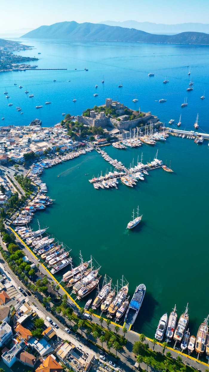 Stunning aerial view of Bodrum Harbor, Turkey, showcasing yachts and St. Peters Castle with clear blue waters.