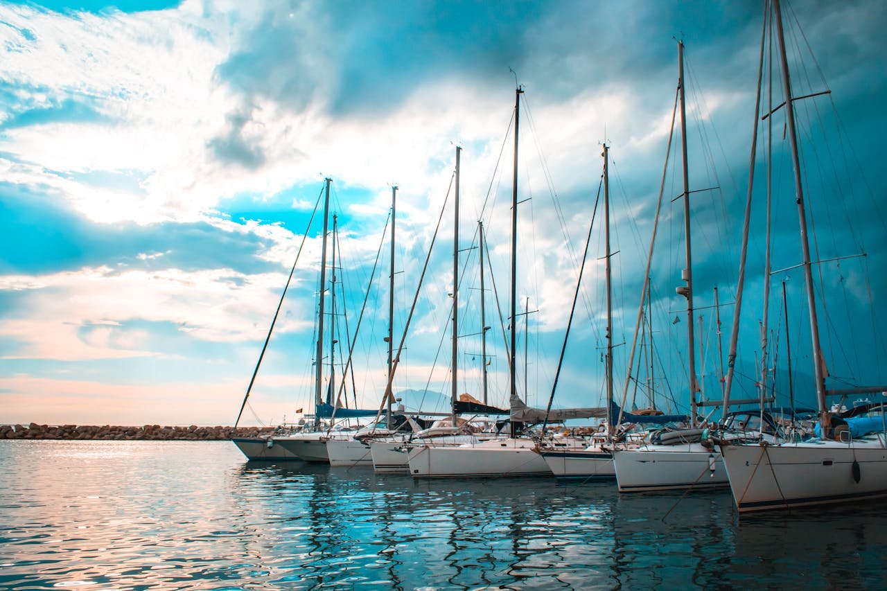 A serene scene of sailboats docked in a picturesque Patra harbour with vibrant sky reflections.